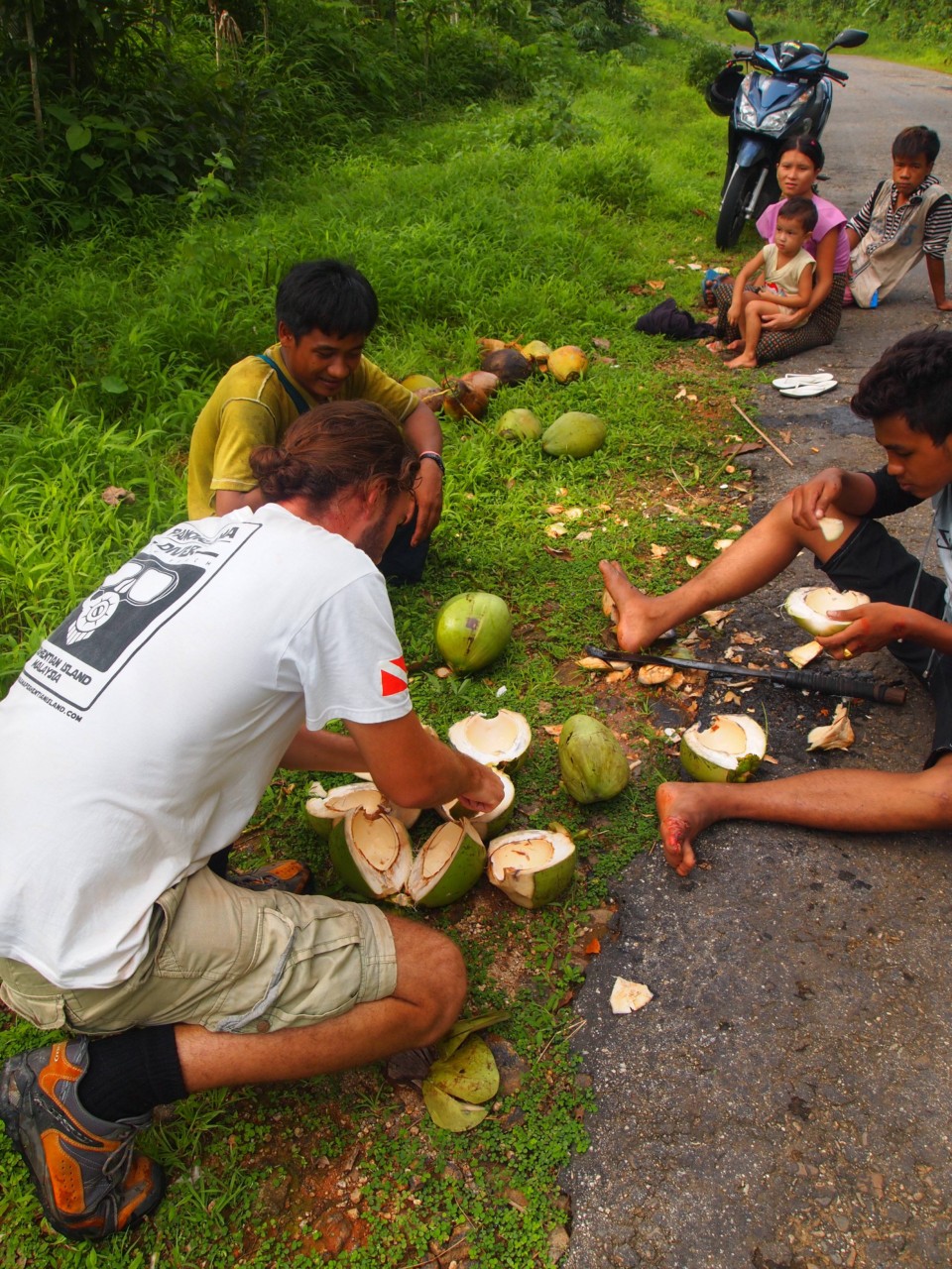 Einheimische schenkten uns Kokosnüssen. Die Leute saßen auf der Straße als wir mit dem Roller vorbei fuhren.